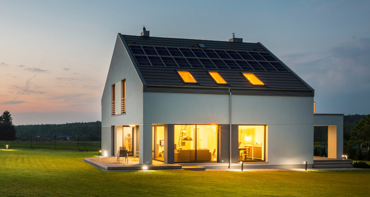A home at dusk powered by solar panels and a Generac PWRcell Whole Home Solar + Battery Storage System with indoor and outdoor lighting